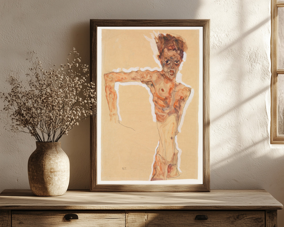Framed art print of Self-Portrait by Egon Schiele, in a dark wood frame leaning on a rustic console beside dried flowers