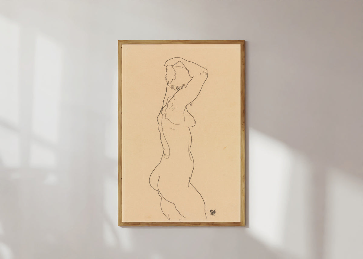 Framed art print of Standing Nude, Facing Right by Egon Schiele, in a light wood frame on a sunlit white wall