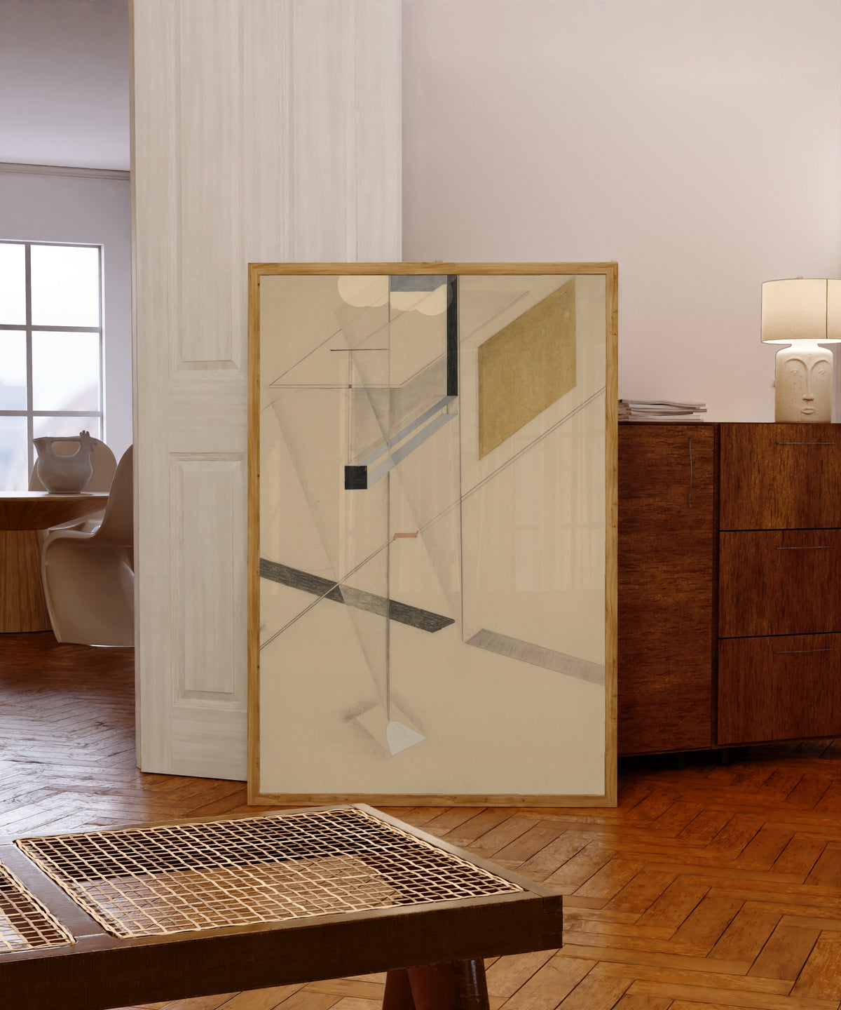 Framed art print of Proun Study l.n. 31 by El Lissitzky, in a light wood frame leaning in a warm room with a parquet floor