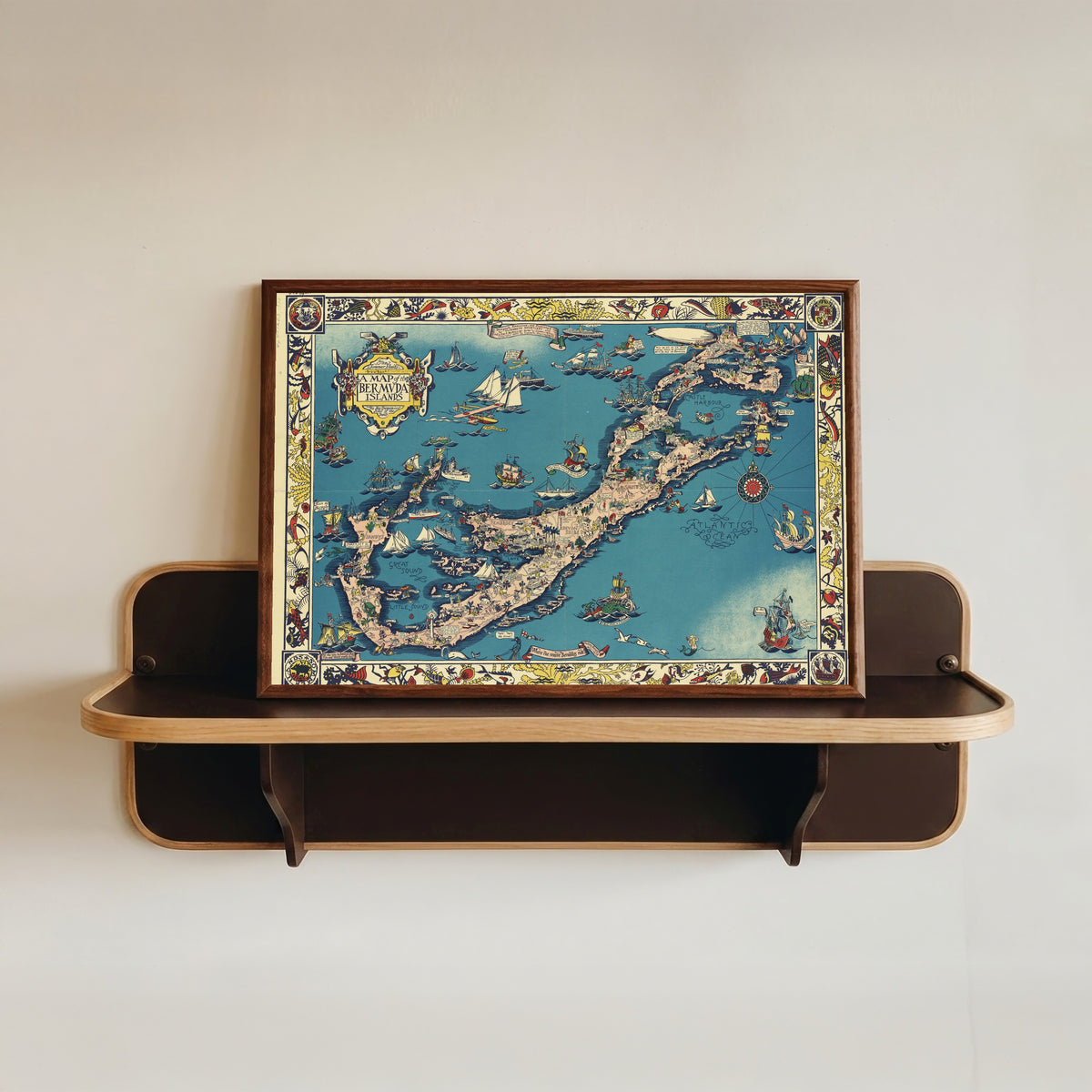Framed art print of A Map of the Bermuda Islands by Elizabeth Shurtleff, in a dark wood frame resting on a wall shelf