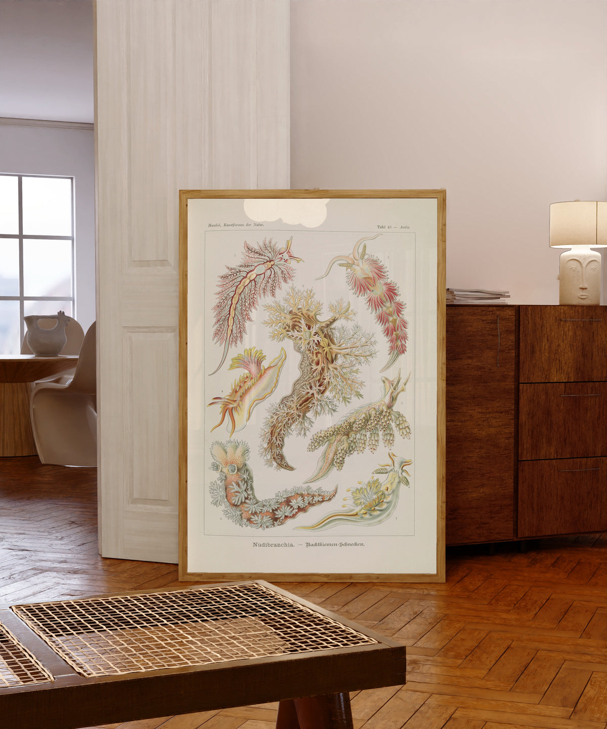 Framed art print of Kunstformen der Natur, Plate 43: Nudibranchia by Ernst Haeckel, in a light wood frame leaning in a warm room with a parquet floor