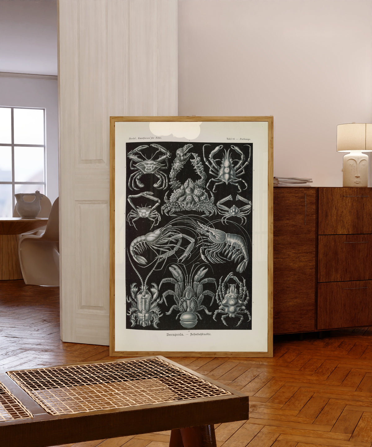 Framed art print of Kunstformen der Natur, Plate 86: Decapoda by Ernst Haeckel, in a light wood frame leaning in a warm room with a parquet floor