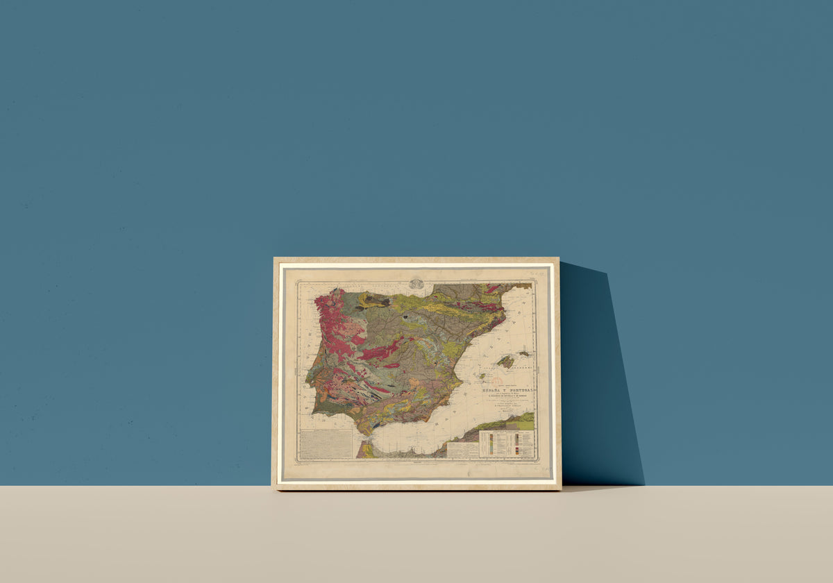 Framed art print of Mapa geológico de España y Portugal by Federico de Botella y de Hornos, in a light wood frame leaning on a blue wall