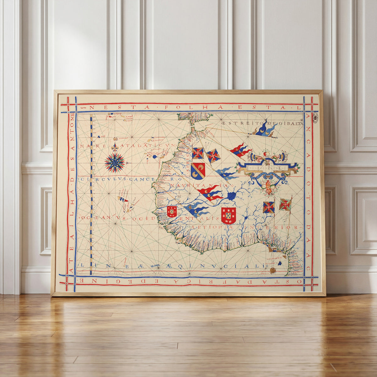 Framed art print of Nautical Chart of West Africa (Vaz Dourado Atlas) by Fernão Vaz Dourado, in a light wood frame leaning against a panelled white wall