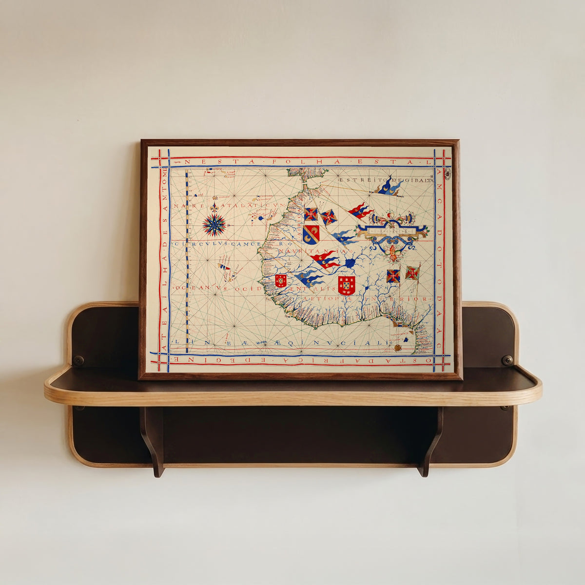 Framed art print of Nautical Chart of West Africa (Vaz Dourado Atlas) by Fernão Vaz Dourado, in a dark wood frame resting on a wall shelf