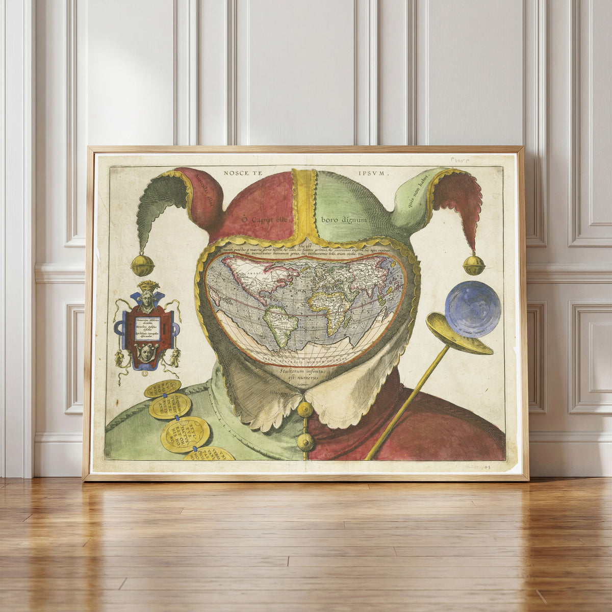 Framed art print of Fool's Cap Map of the World, in a light wood frame leaning against a panelled white wall