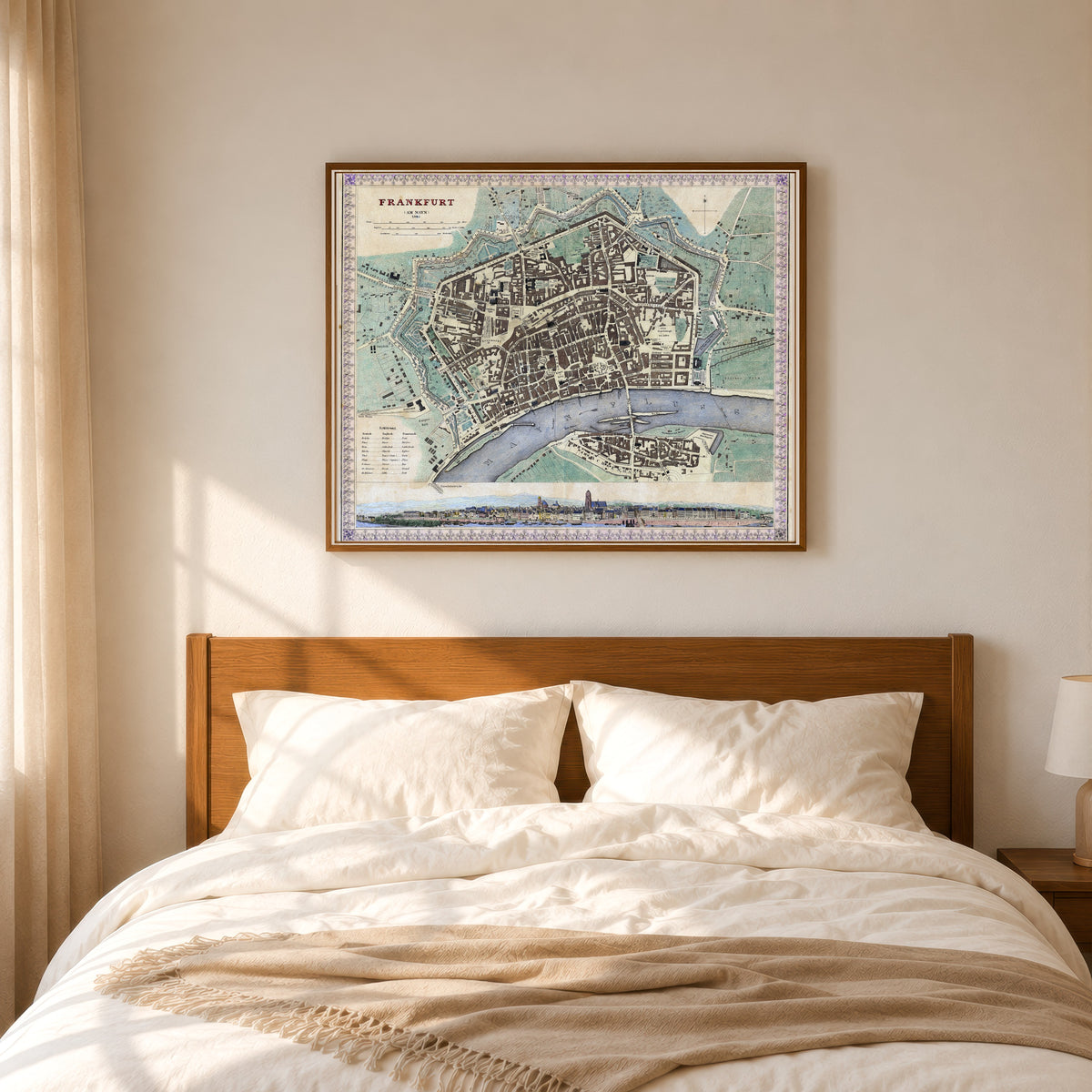 Framed art print of Frankfurt am Main, in a slim wood frame above a bed in a sunlit bedroom