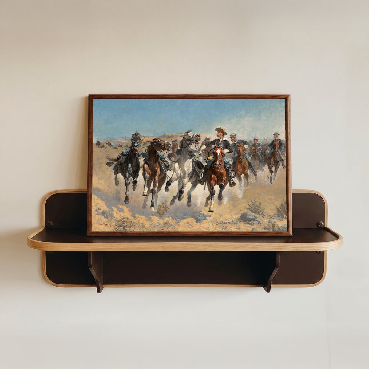 Framed art print of Dismounted: The Fourth Troopers Moving the Led Horses by Frederic Remington, in a dark wood frame resting on a wall shelf