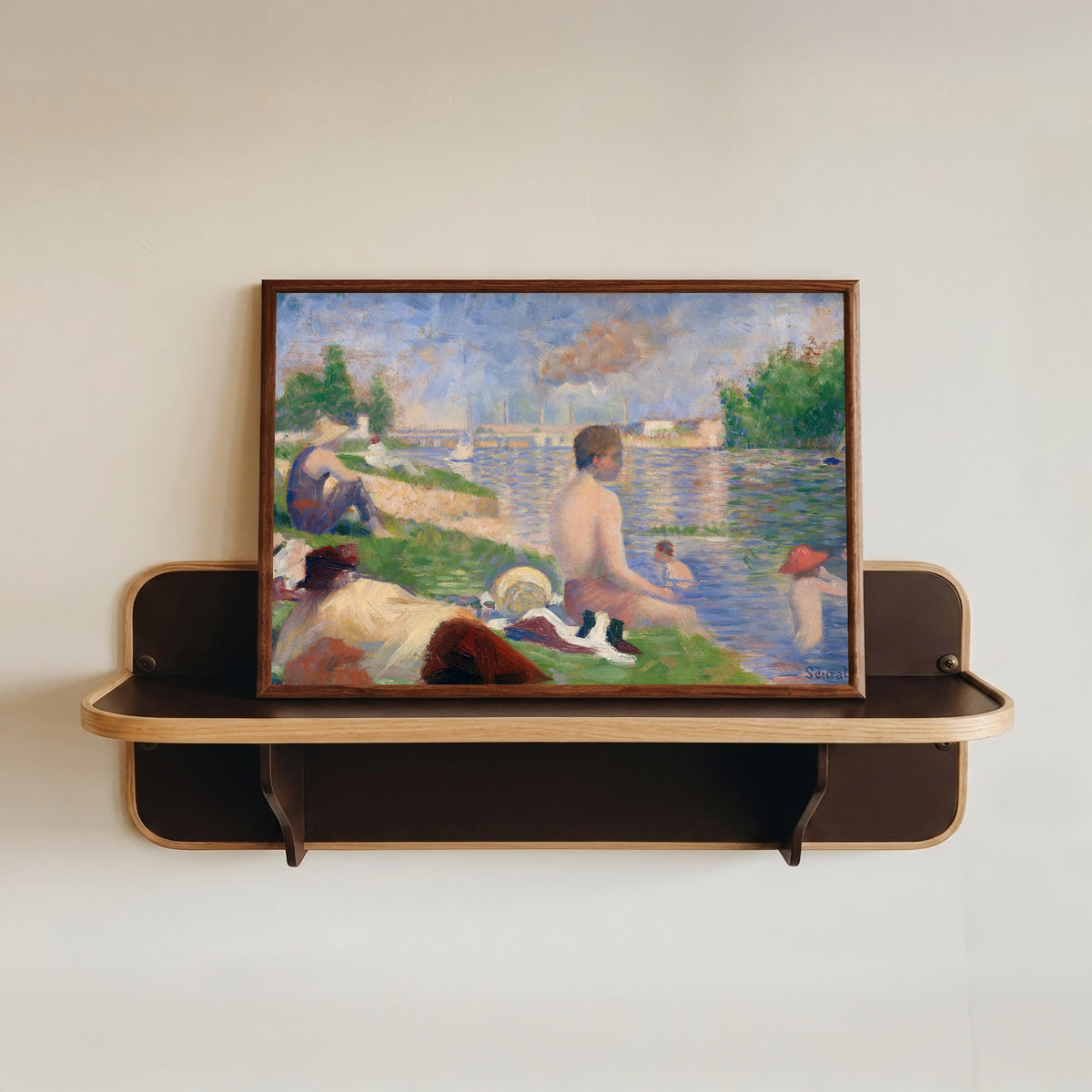 Framed art print of Final Study for Bathers at Asnieres by Georges Seurat, in a dark wood frame resting on a wall shelf