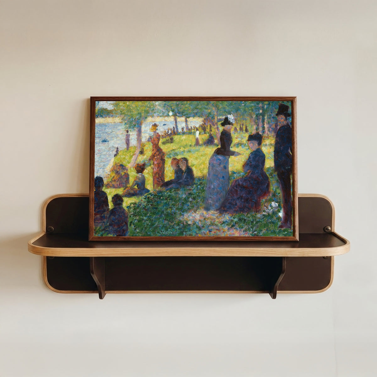 Framed art print of Oil Sketch for A Sunday on La Grande Jatte by Georges Seurat, in a dark wood frame resting on a wall shelf