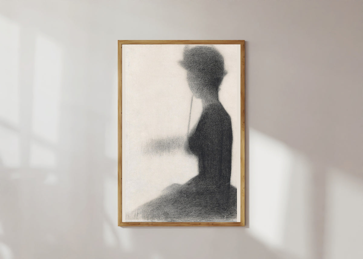 Framed art print of Seated Woman with a Parasol (study for La Grande Jatte) by Georges Seurat, in a light wood frame on a sunlit white wall