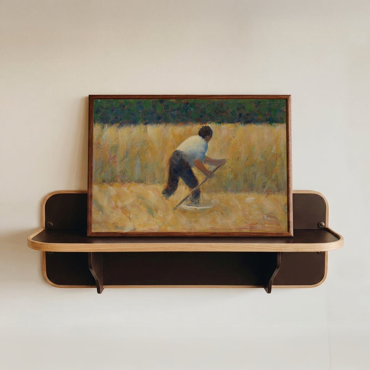 Framed art print of The Mower by Georges Seurat, in a dark wood frame resting on a wall shelf