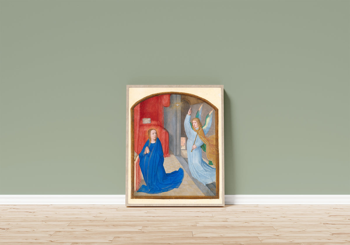 Framed art print of The Annunciation by Gerard David (circle of), in a light wood frame leaning on a sage green wall above a wooden floor