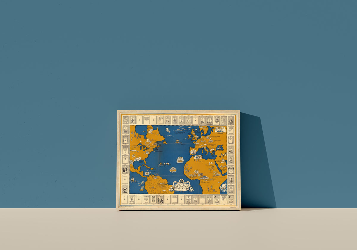 Framed art print of A Map of the World of Books by Ginn and Company, in a light wood frame leaning on a blue wall