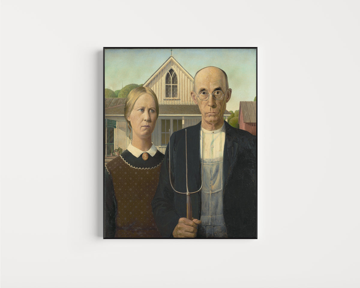 Framed art print of American Gothic by Grant Wood, in a slim black frame on a plain white wall
