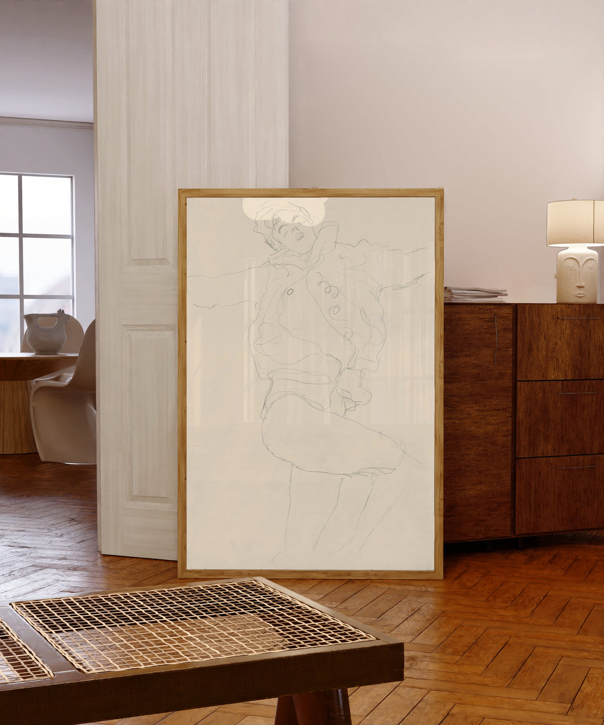 Framed art print of Dancing Woman with Cape by Gustav Klimt, in a light wood frame leaning in a warm room with a parquet floor