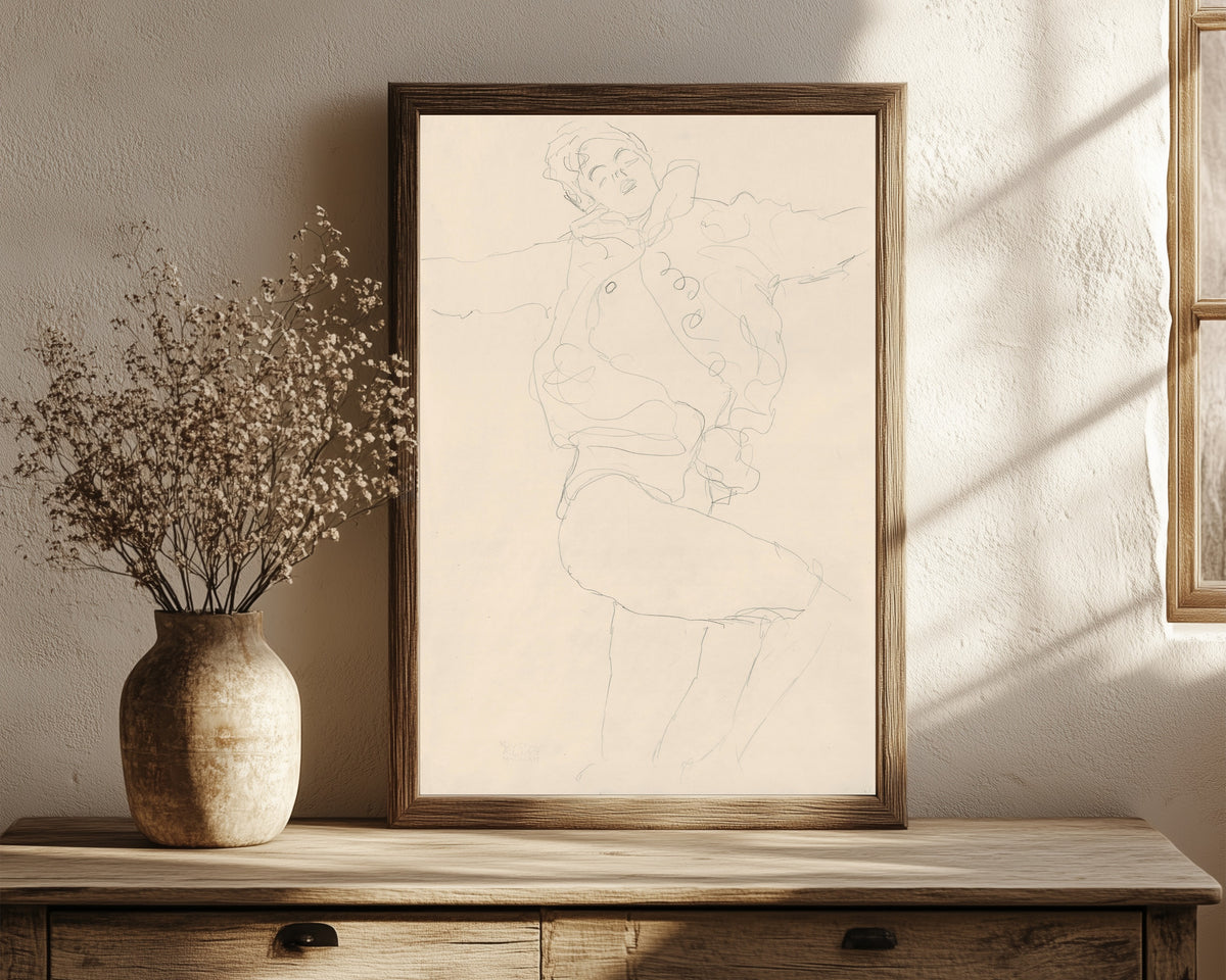 Framed art print of Dancing Woman with Cape by Gustav Klimt, in a dark wood frame leaning on a rustic console beside dried flowers