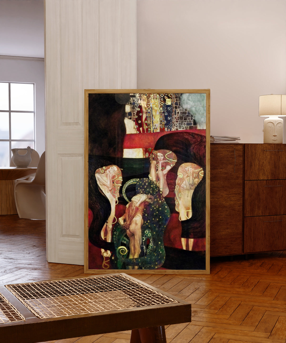 Framed art print of Jurisprudence by Gustav Klimt, in a light wood frame leaning in a warm room with a parquet floor