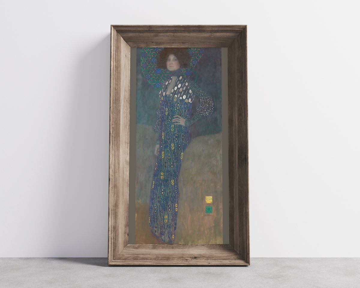 Framed art print of Portrait of Emilie Flöge by Gustav Klimt, in a wide wooden frame leaning against a concrete wall