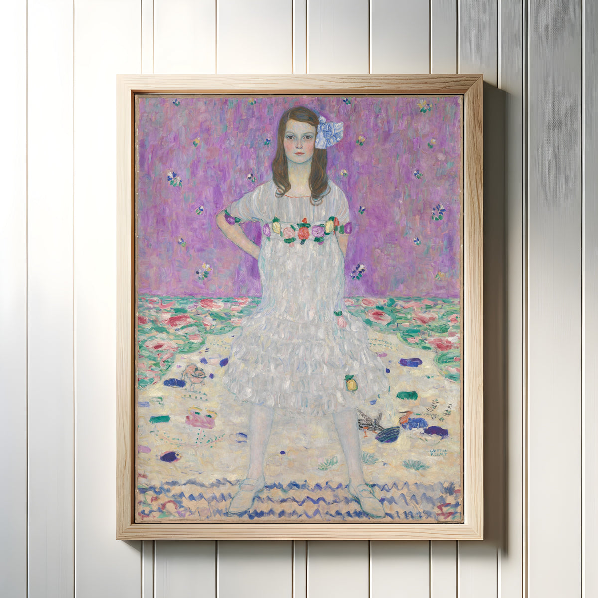 Framed art print of Portrait of Mäda Primavesi by Gustav Klimt, in a light wood frame on a white panelled wall