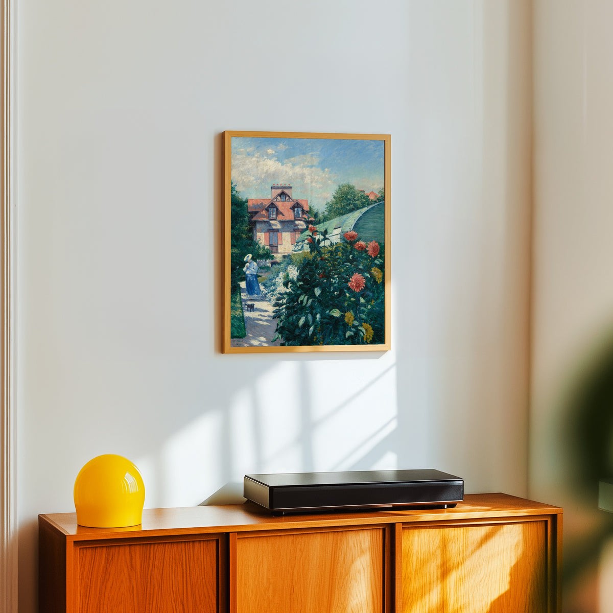 Framed art print of Dahlias, Garden at Petit Gennevilliers by Gustave Caillebotte, in a light wood frame on a white wall above an orange sideboard
