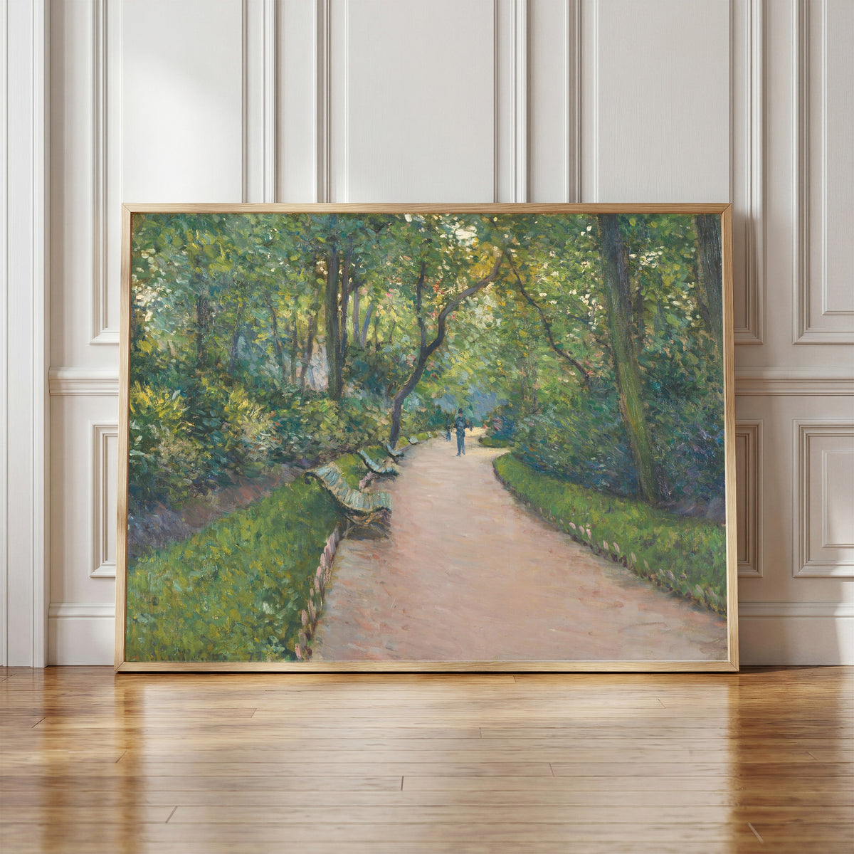 Framed art print of Le Parc Monceau by Gustave Caillebotte, in a light wood frame leaning against a panelled white wall