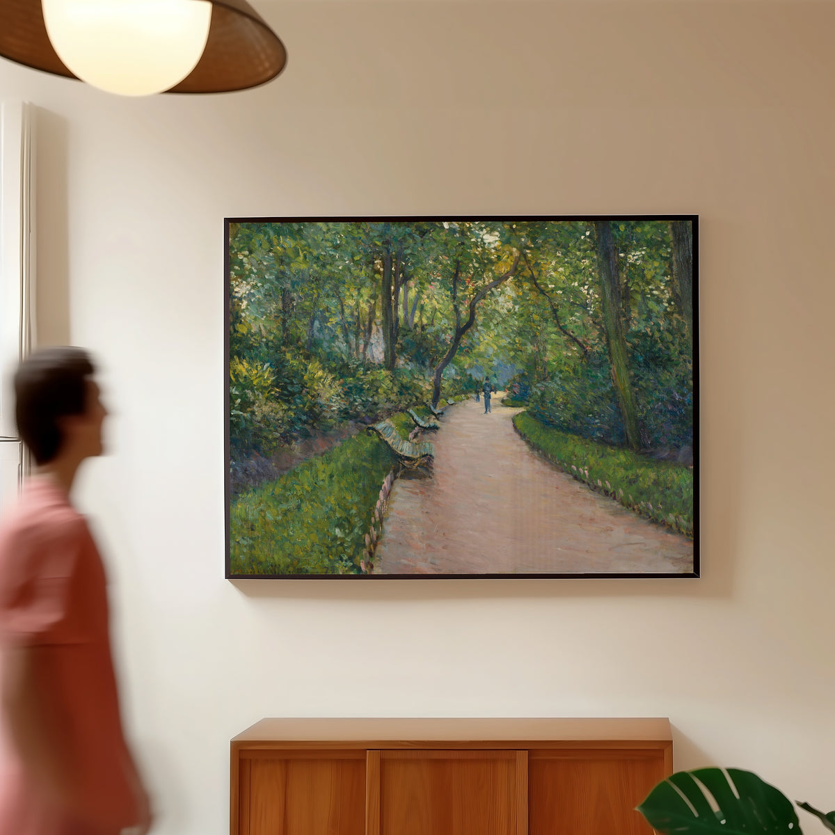 Framed art print of Le Parc Monceau by Gustave Caillebotte, in a slim black frame on a warm wall in a sunlit room