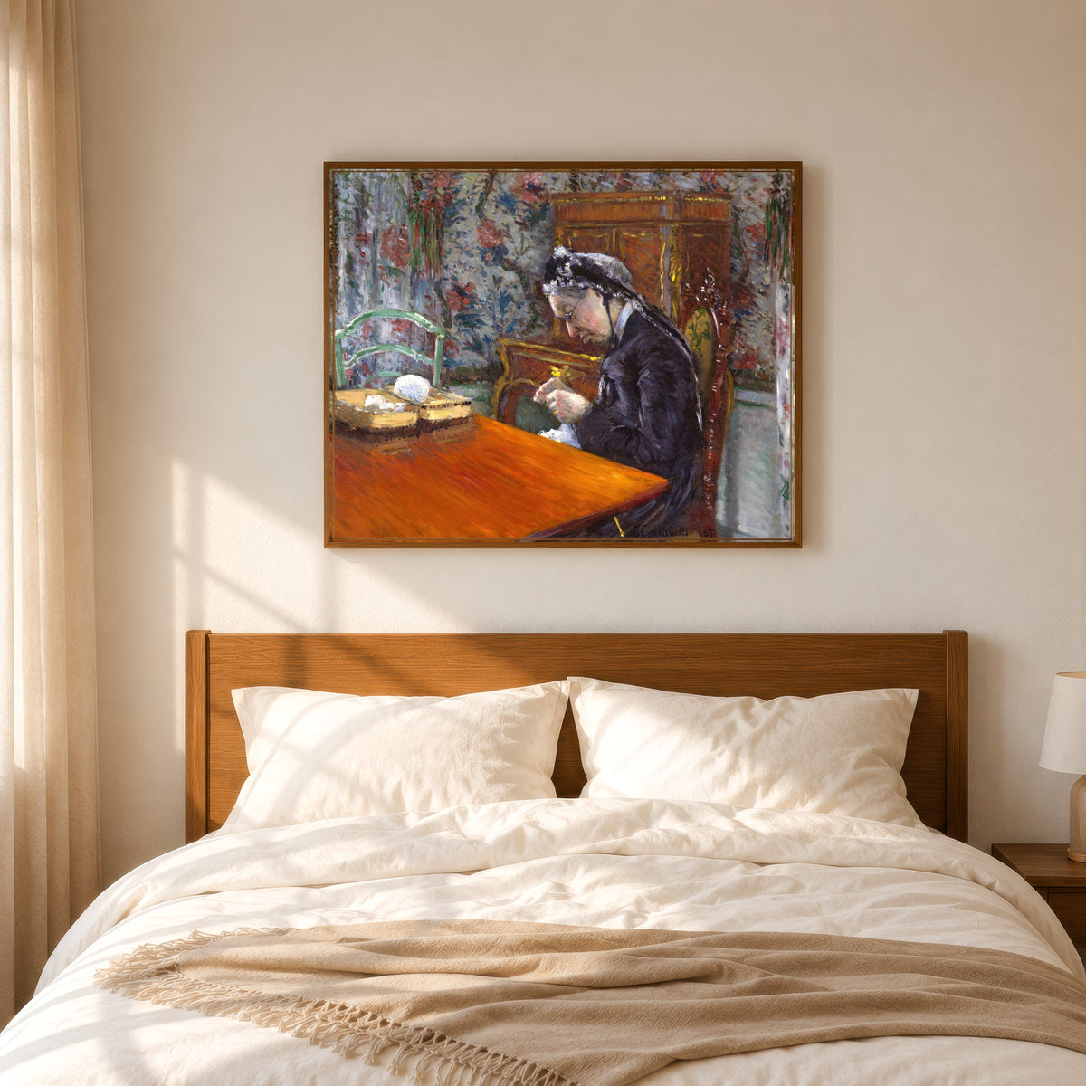 Framed art print of Mademoiselle Boissière Knitting by Gustave Caillebotte, in a slim wood frame above a bed in a sunlit bedroom