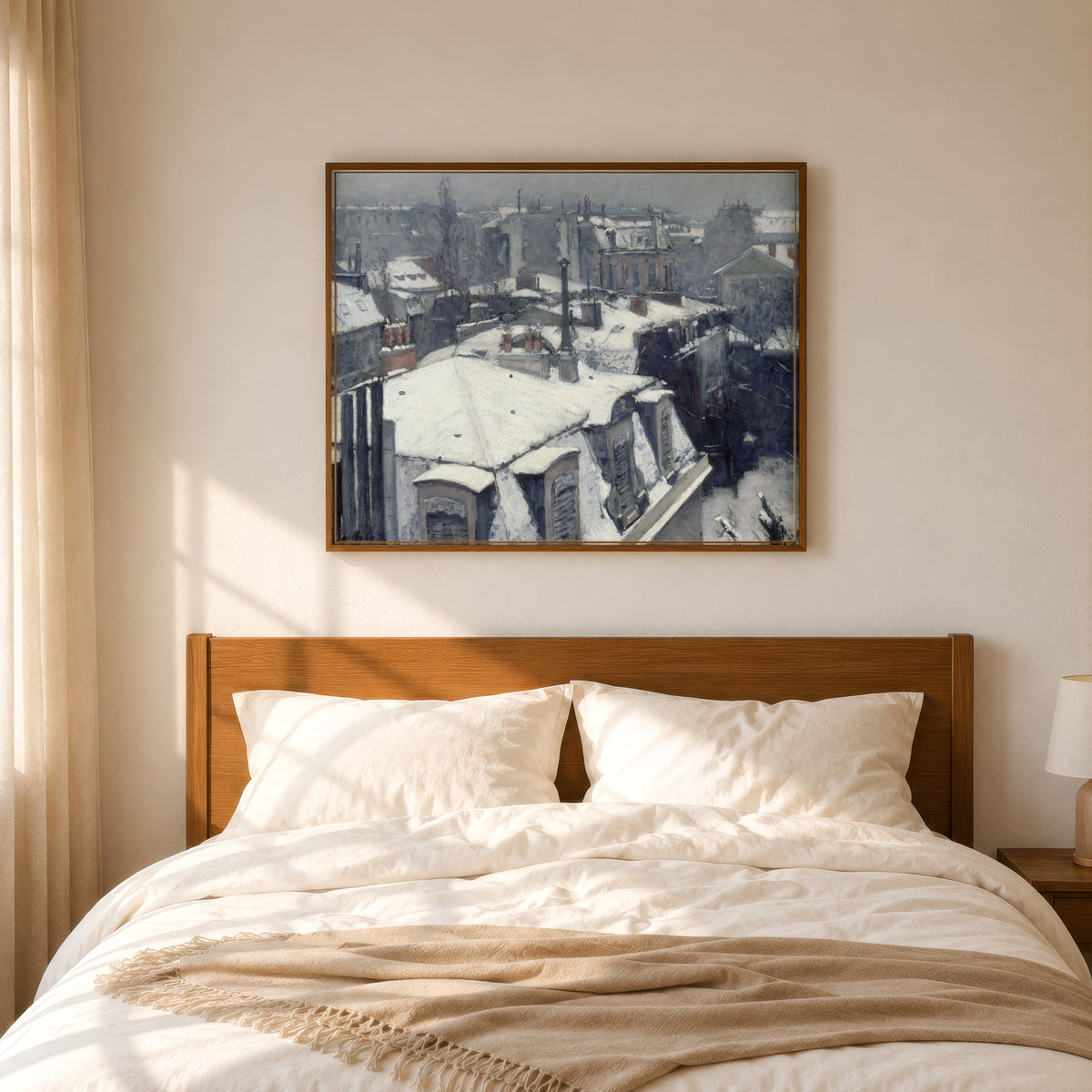 Framed art print of Rooftops in the Snow (Snow Effect) by Gustave Caillebotte, in a slim wood frame above a bed in a sunlit bedroom
