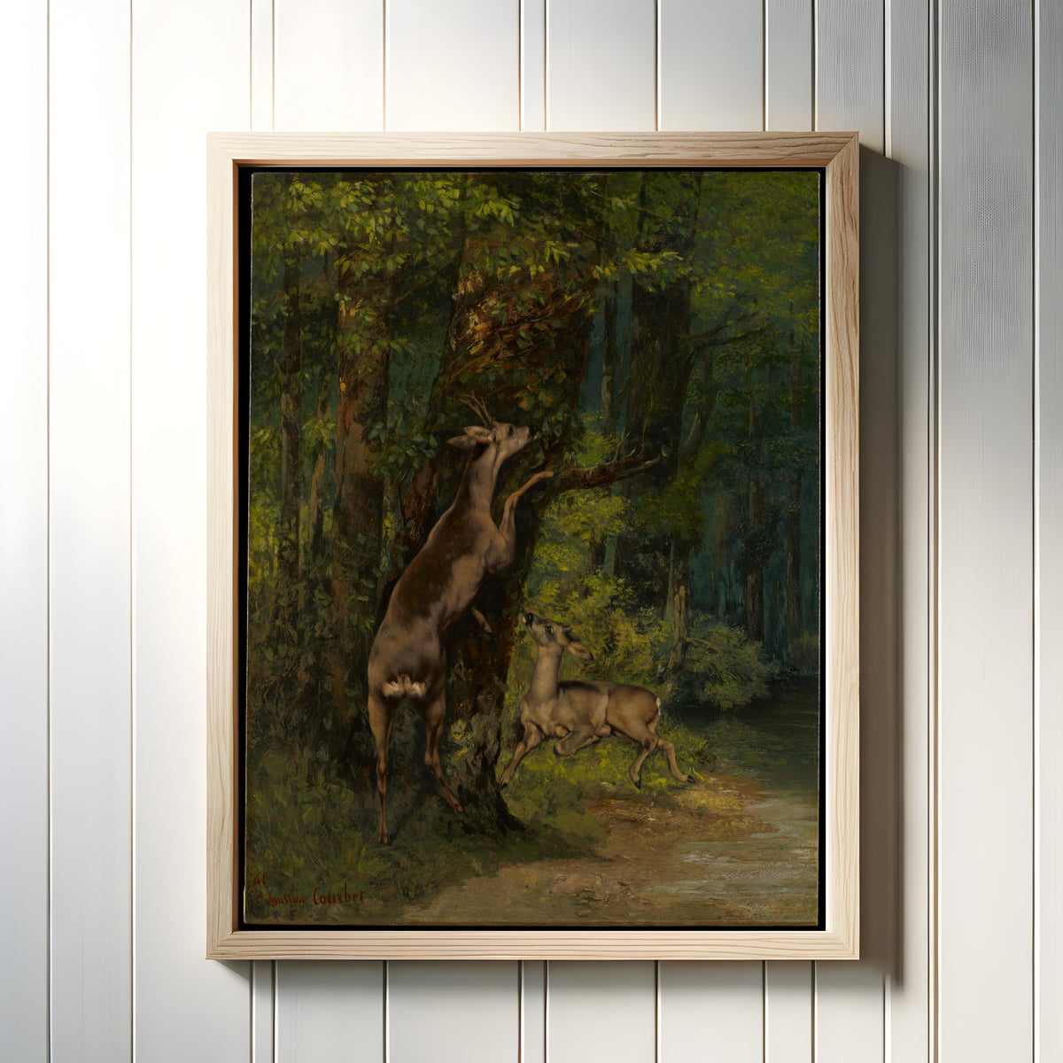 Framed art print of Deer in the Forest by Gustave Courbet, in a light wood frame on a white panelled wall