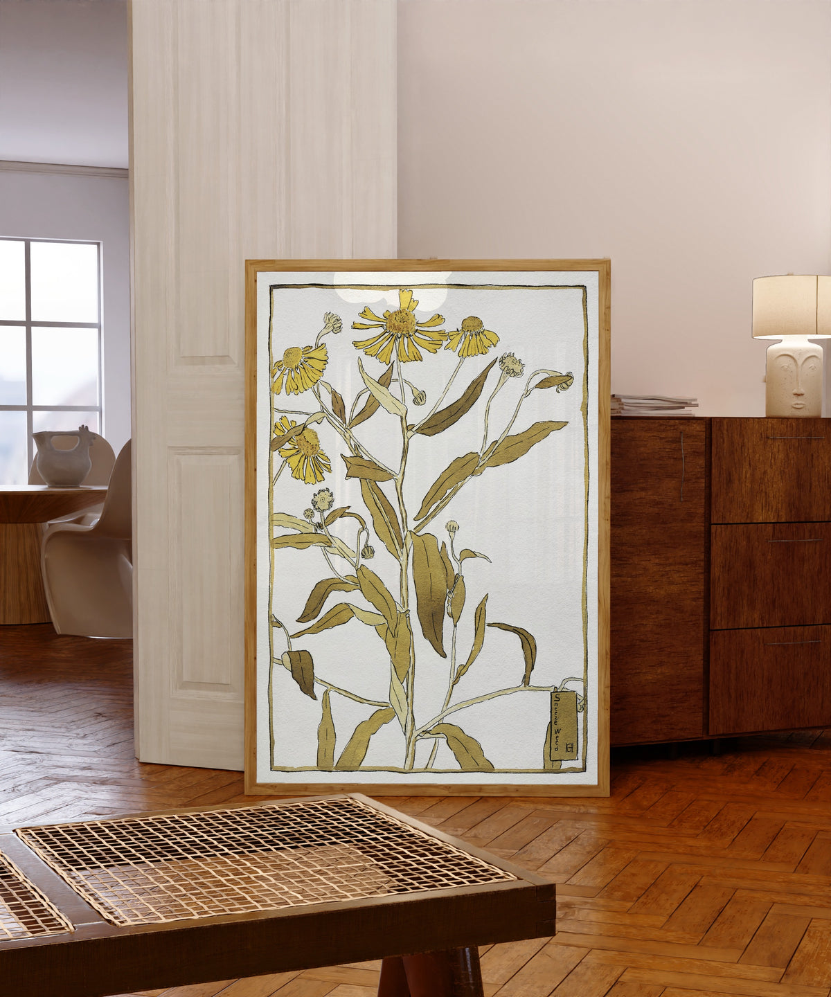 Framed art print of Sneeze Weed by Hannah Borger Overbeck, in a light wood frame leaning in a warm room with a parquet floor