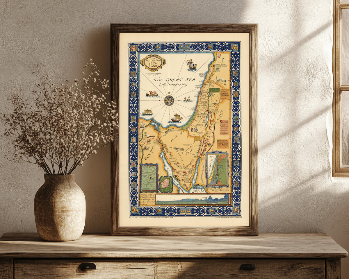 Framed art print of The Picture Map of the Holy Land by Harold Haven Brown, in a dark wood frame leaning on a rustic console beside dried flowers