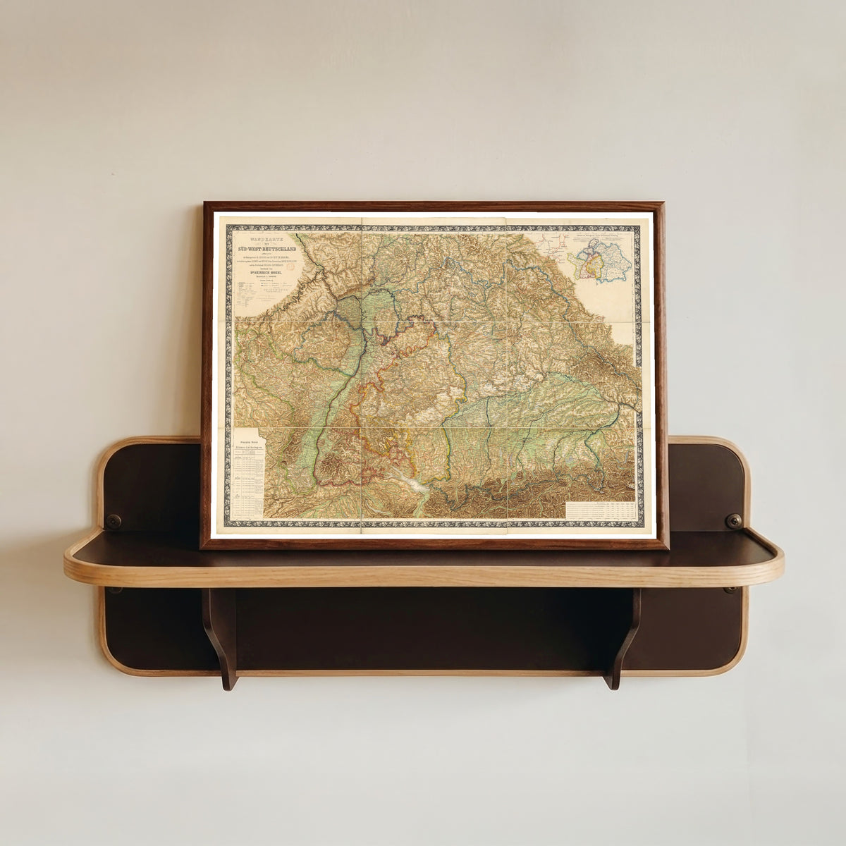 Framed art print of Wall Map of South-West Germany (Wandkarte von Süd-West-Deutschland) by Heinrich Moehl, in a dark wood frame resting on a wall shelf