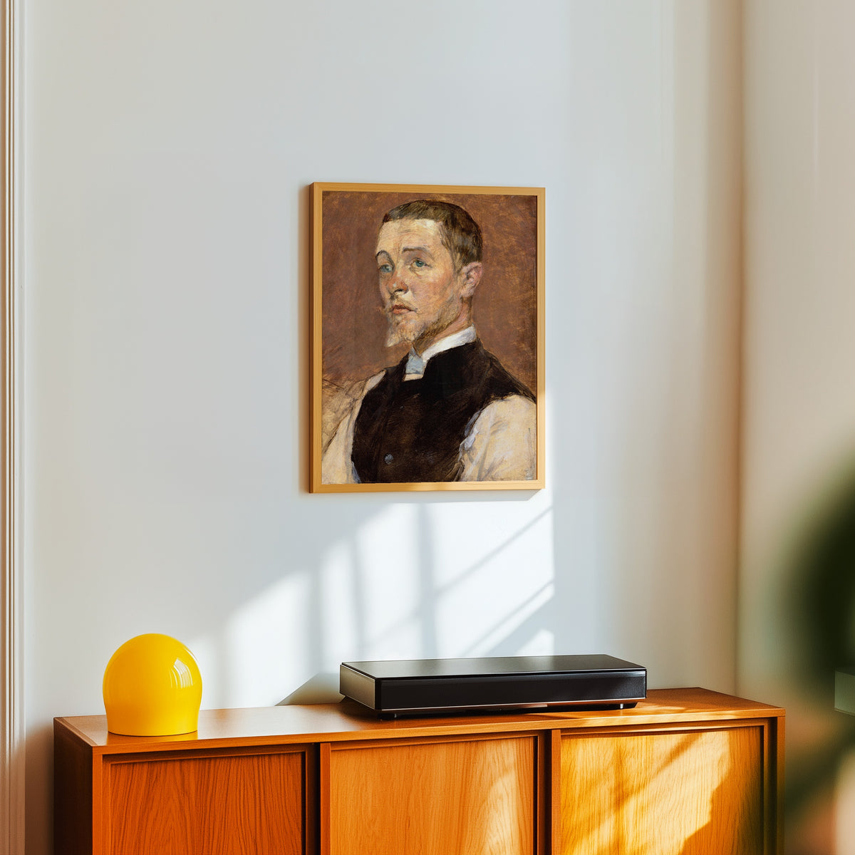 Framed art print of Albert (René) Grenier by Henri de Toulouse-Lautrec, in a light wood frame on a white wall above an orange sideboard