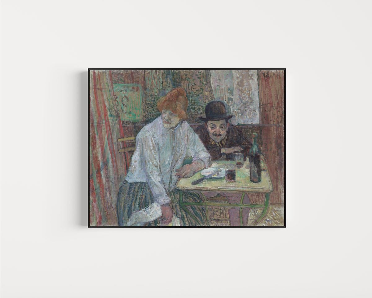 Framed art print of At the Café La Mie by Henri de Toulouse-Lautrec, in a slim black frame on a plain white wall