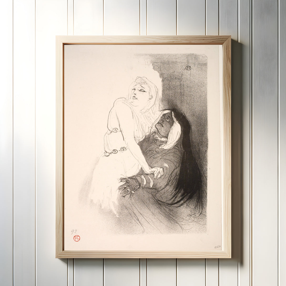 Framed art print of At the Renaissance: Sarah Bernhardt in Phèdre by Henri de Toulouse-Lautrec, in a light wood frame on a white panelled wall