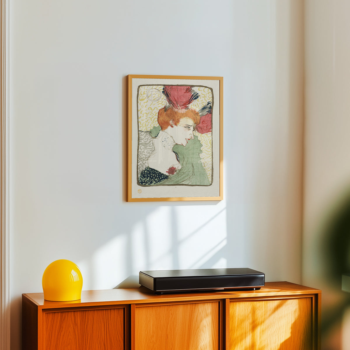 Framed art print of Bust of Mademoiselle Lender by Henri de Toulouse-Lautrec, in a light wood frame on a white wall above an orange sideboard