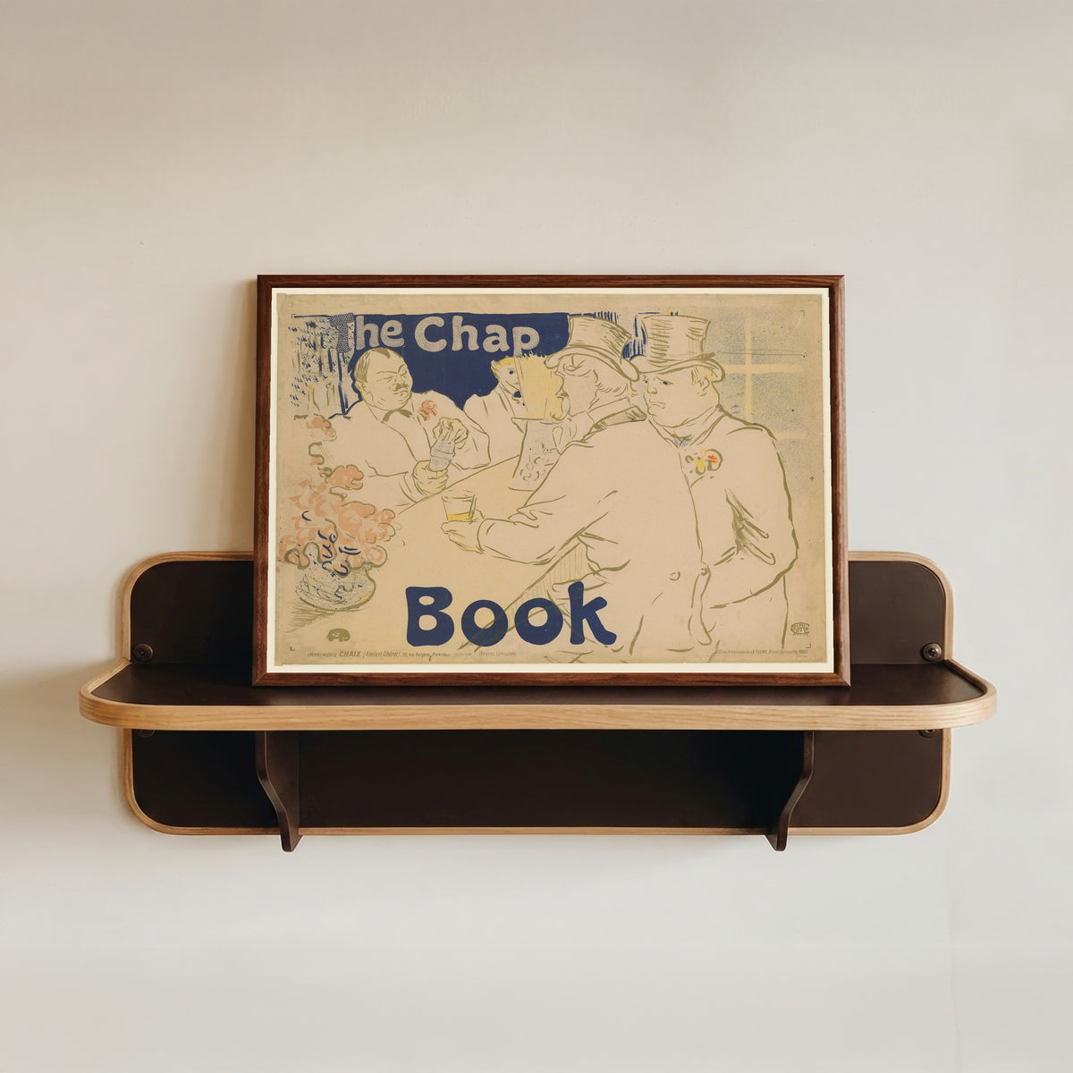 Framed art print of Irish and American Bar, Rue Royale: The Chap Book by Henri de Toulouse-Lautrec, in a dark wood frame resting on a wall shelf