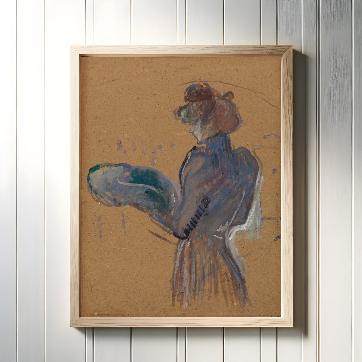 Framed art print of La Modiste, Mademoiselle Margouin by Henri de Toulouse-Lautrec, in a light wood frame on a white panelled wall