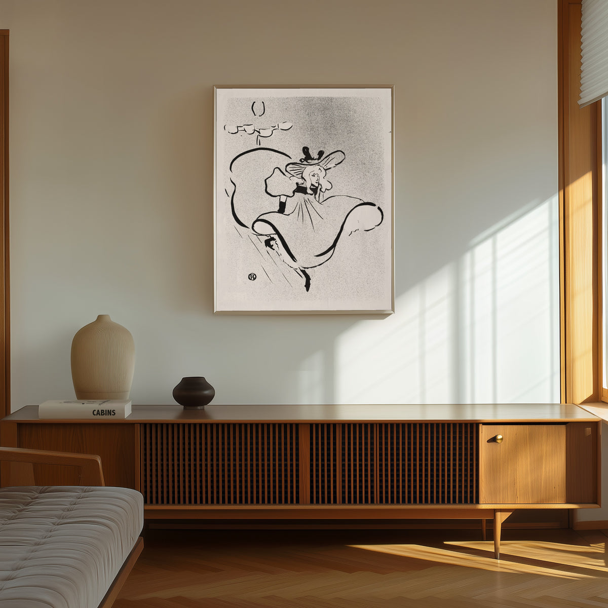 Framed art print of Le Café-Concert: Jane Avril by Henri de Toulouse-Lautrec, in a thin light frame on a sunlit wall above a wooden sideboard