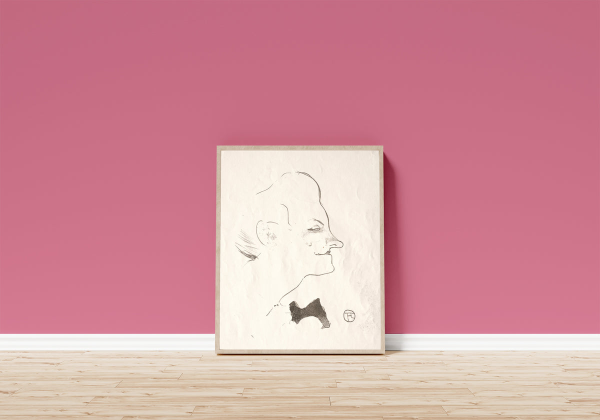 Framed art print of Le Café-Concert: Yvette Guilbert by Henri de Toulouse-Lautrec, in a light wood frame leaning on a pink wall above a wooden floor