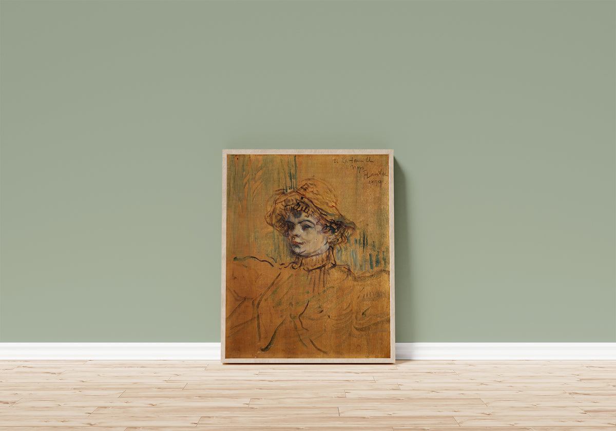 Framed art print of Mademoiselle Nys by Henri de Toulouse-Lautrec, in a light wood frame leaning on a sage green wall above a wooden floor