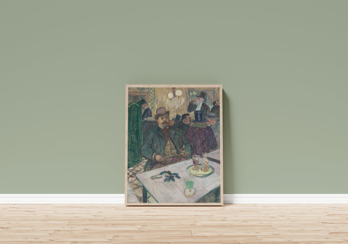 Framed art print of Monsieur Boileau at the Café by Henri de Toulouse-Lautrec, in a light wood frame leaning on a sage green wall above a wooden floor