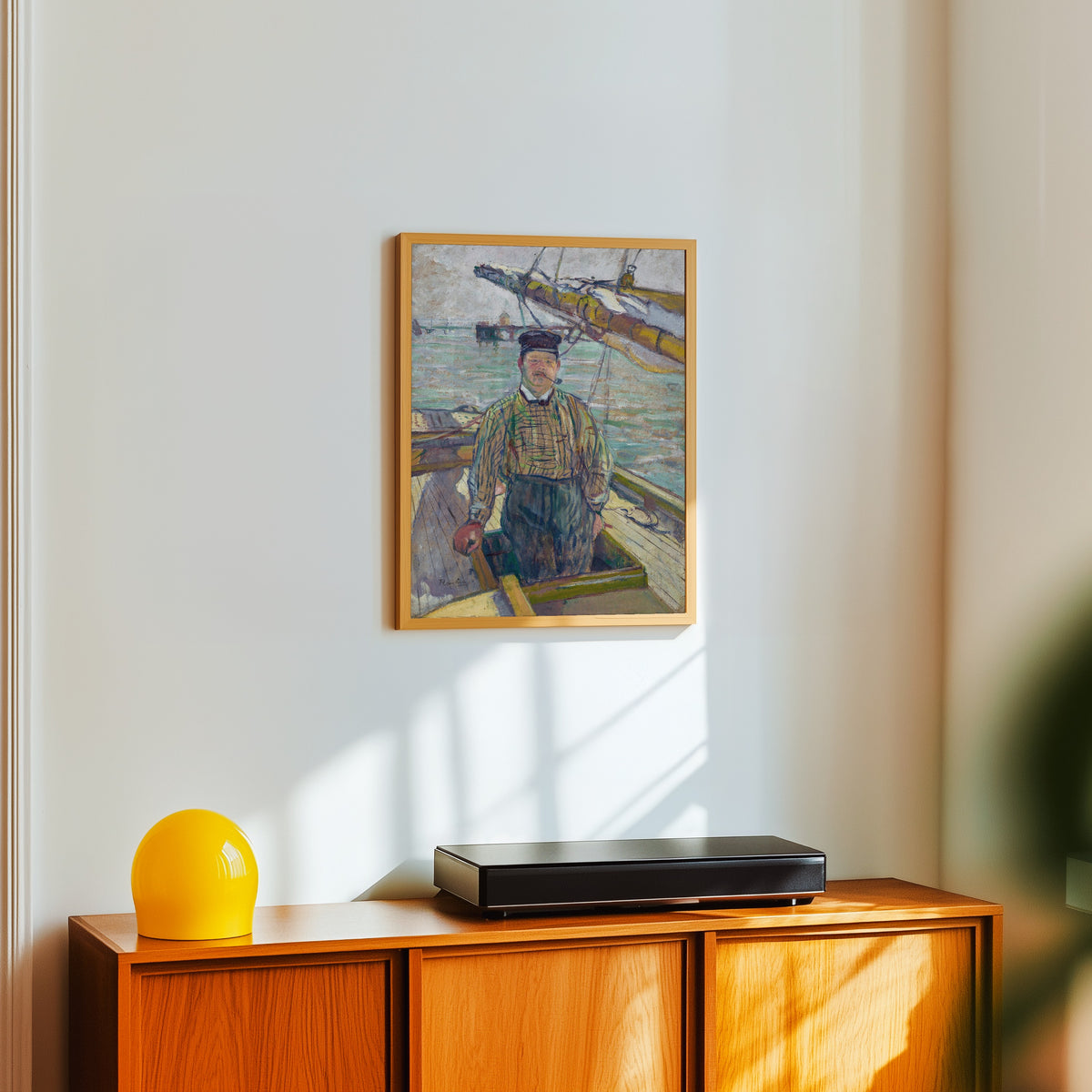 Framed art print of Monsieur Emile Davoust by Henri de Toulouse-Lautrec, in a light wood frame on a white wall above an orange sideboard