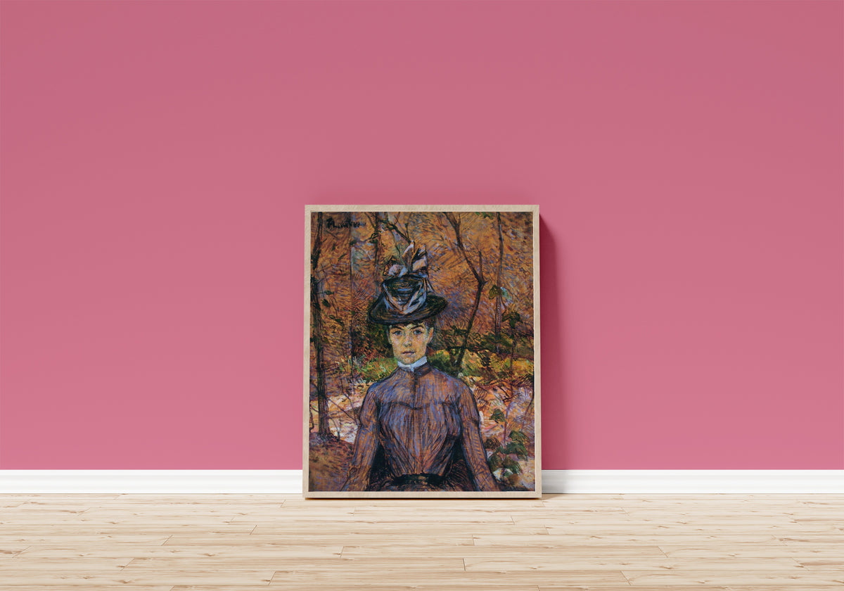 Framed art print of Portrait of Suzanne Valadon by Henri de Toulouse-Lautrec, in a light wood frame leaning on a pink wall above a wooden floor