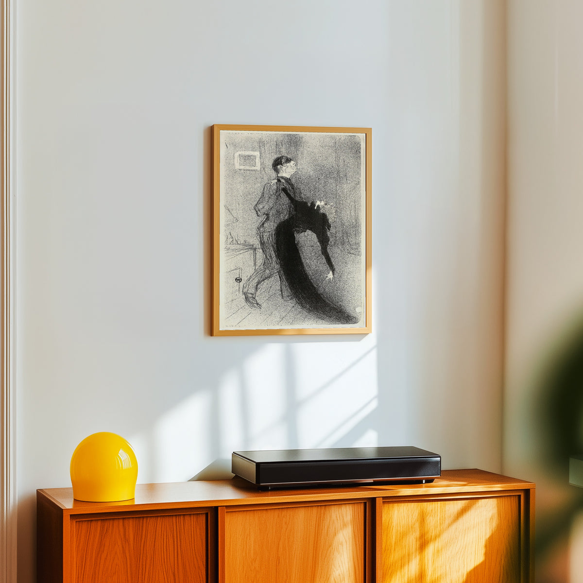 Framed art print of The Fainting Fit by Henri de Toulouse-Lautrec, in a light wood frame on a white wall above an orange sideboard