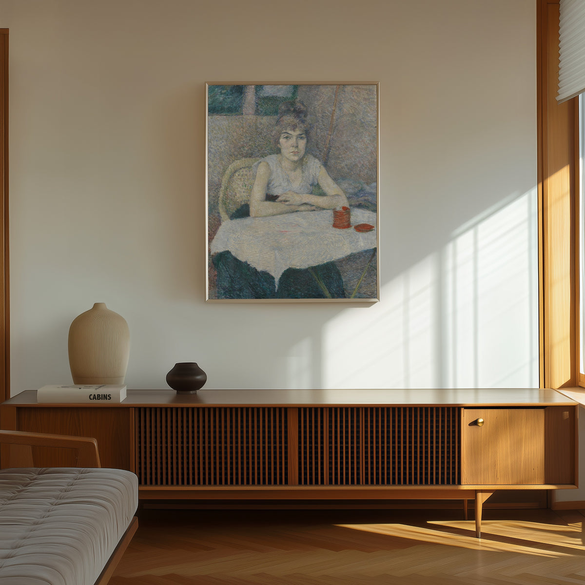 Framed art print of Young Woman at a Table, 'Poudre de riz' by Henri de Toulouse-Lautrec, in a thin light frame on a sunlit wall above a wooden sideboard