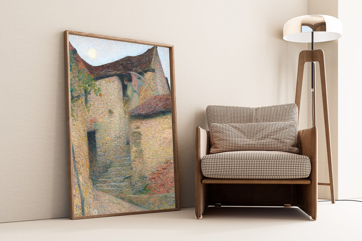 Framed art print of Charité by Henri Martin, leaning against a wall beside an armchair and a floor lamp