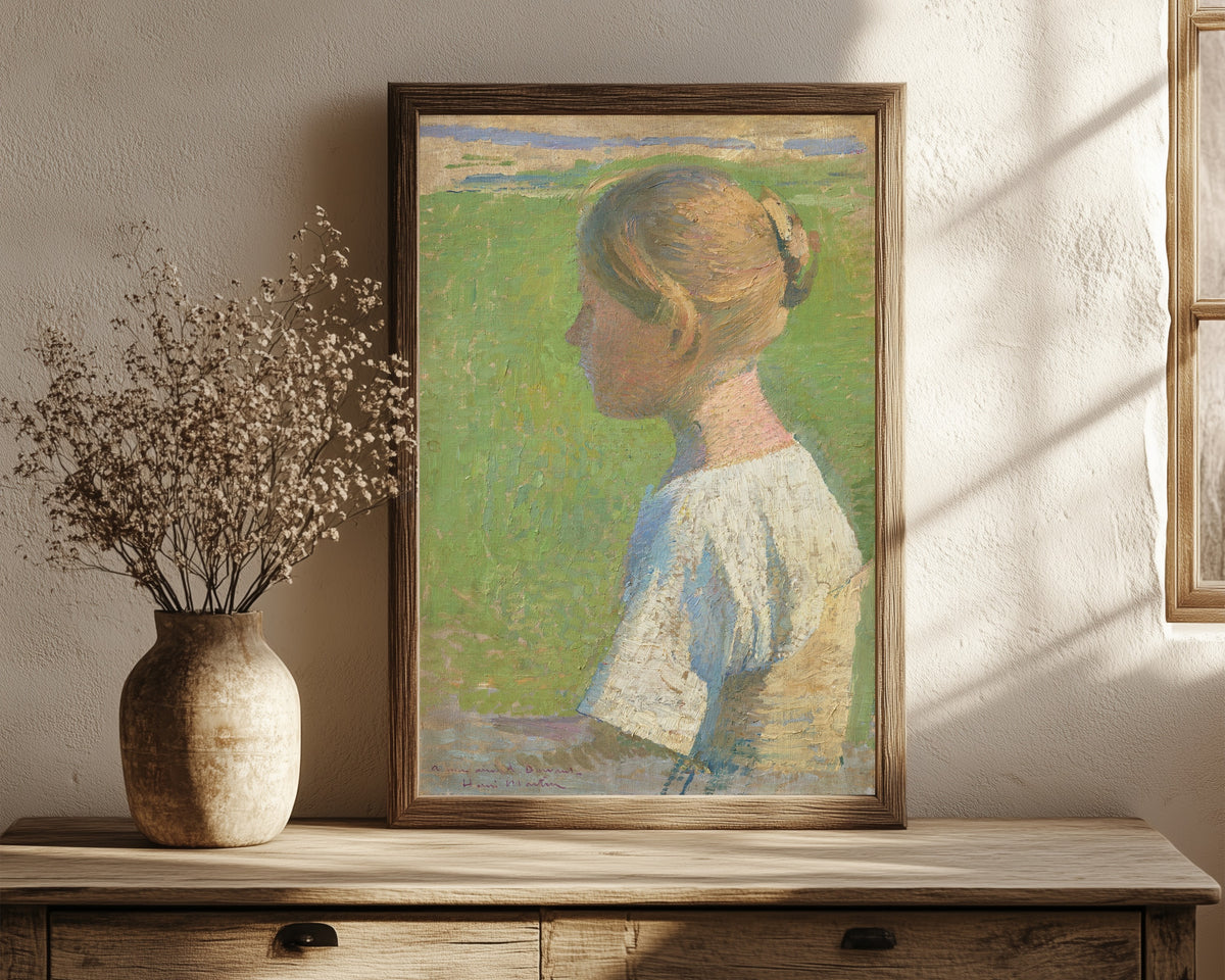 Framed art print of Jeune femme de profil by Henri Martin, in a dark wood frame leaning on a rustic console beside dried flowers
