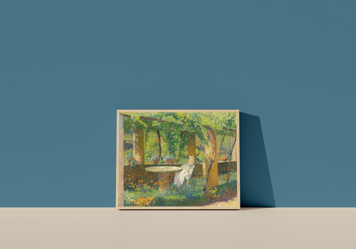 Framed art print of La Tonnelle de Marquayrol by Henri Martin, in a light wood frame leaning on a blue wall